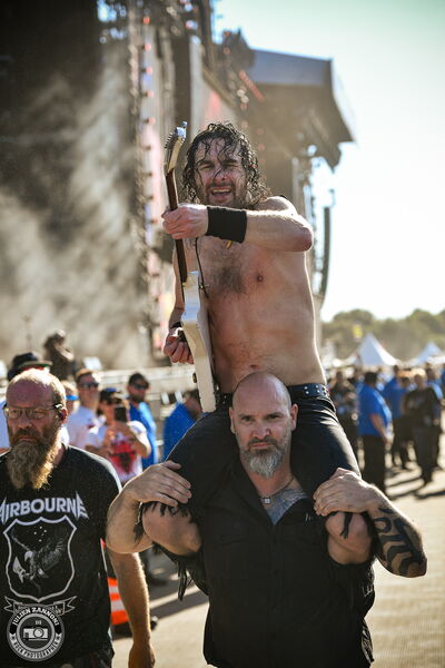 Joel O'Keeffe of Airbourne playing a guitar solo on a security guard's shoulders in the crowd at Wacken Open Air 2026.
